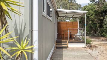 Uma casa moderna com varanda coberta, deck de madeira e caminho de concreto.