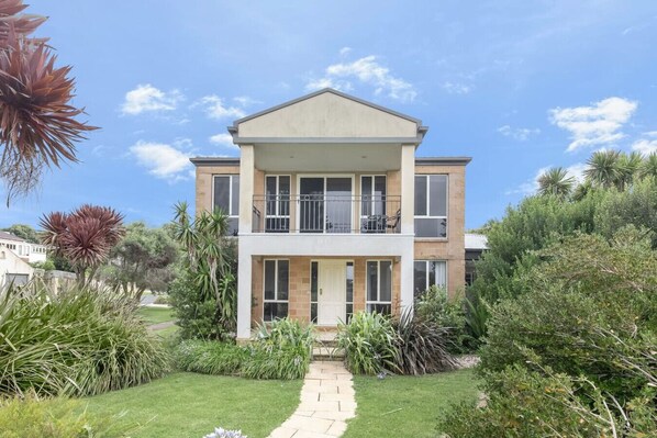 A two-story residential building with a balcony on the upper floor, surrounded by a well-maintained garden. - 4 BR house near beach sleeps 9 (Warrnambool)