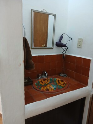 A bathroom with a tiled sink, a mirror, and a towel hanging on the wall.
