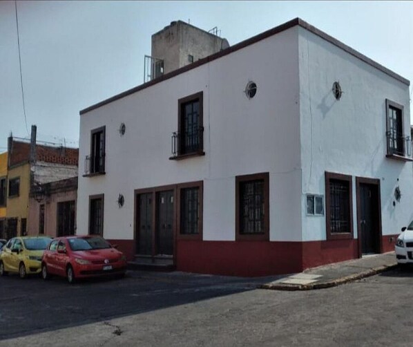 A two-story building with a red and white facade, featuring a central entrance with a door and windows on the ground floor.