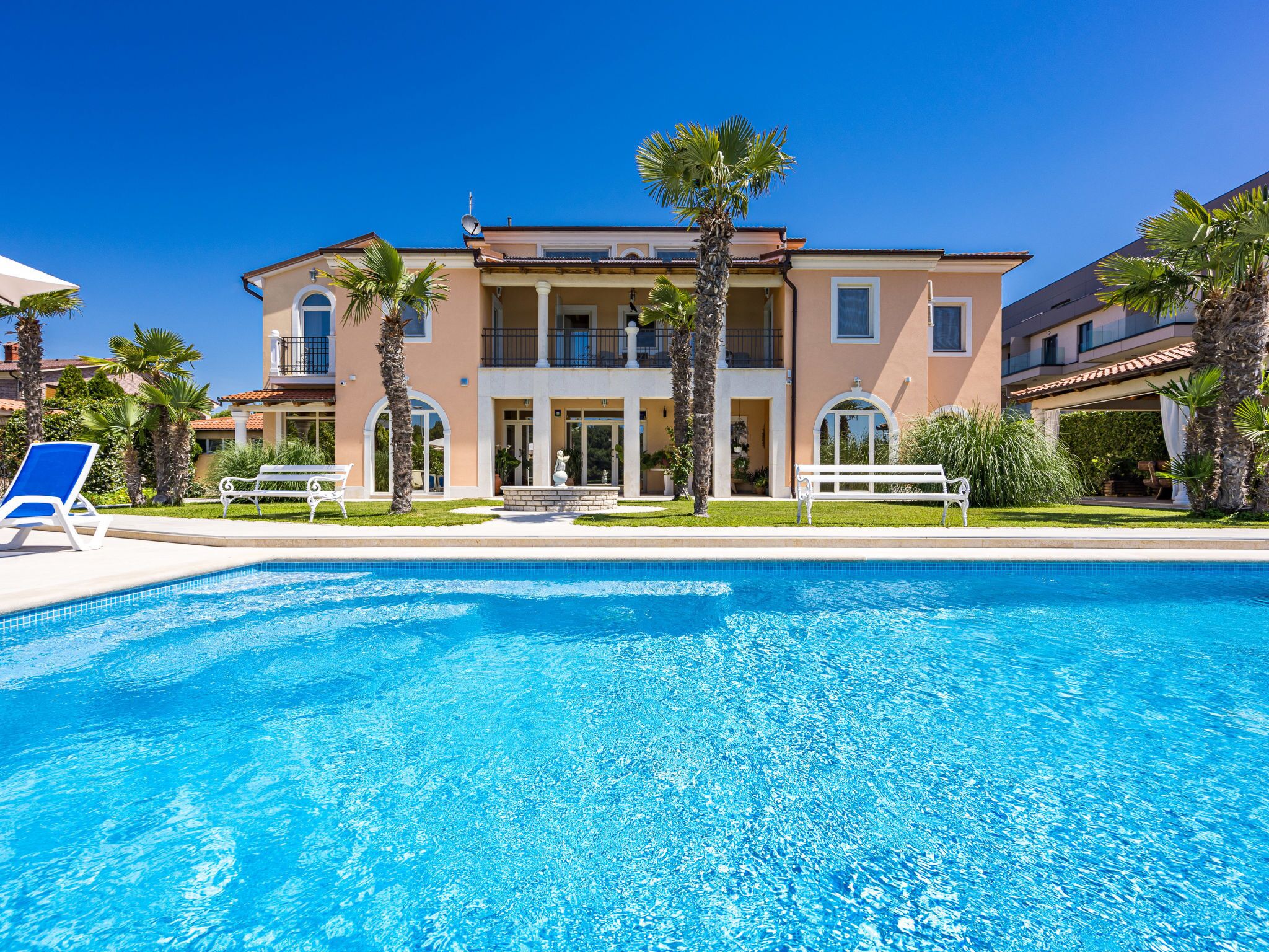 Une grande maison à deux étages avec une piscine à l’avant.