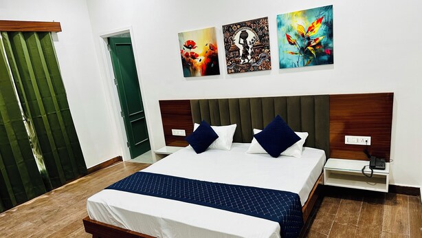 A modern hotel room with a large bed, wooden headboard, and three wall-mounted artworks.