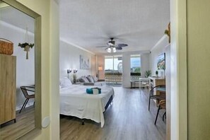 Relax in this spacious room with a large bed, seating area, and a window offering a view of the outdoors.