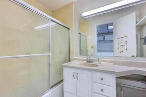 Bathroom features a large mirror above a vanity with a sink and cabinet.