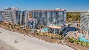 Een hoog hotelcomplex met meerdere gebouwen, een zwembad en een strandgedeelte.