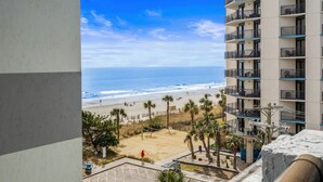 Een hoog hotel met balkons met uitzicht op een strand.