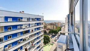 A multi-story building with balconies, a view of the sea, and a parking area below.