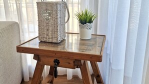 A wooden table with a woven basket and a potted plant on a glass top.