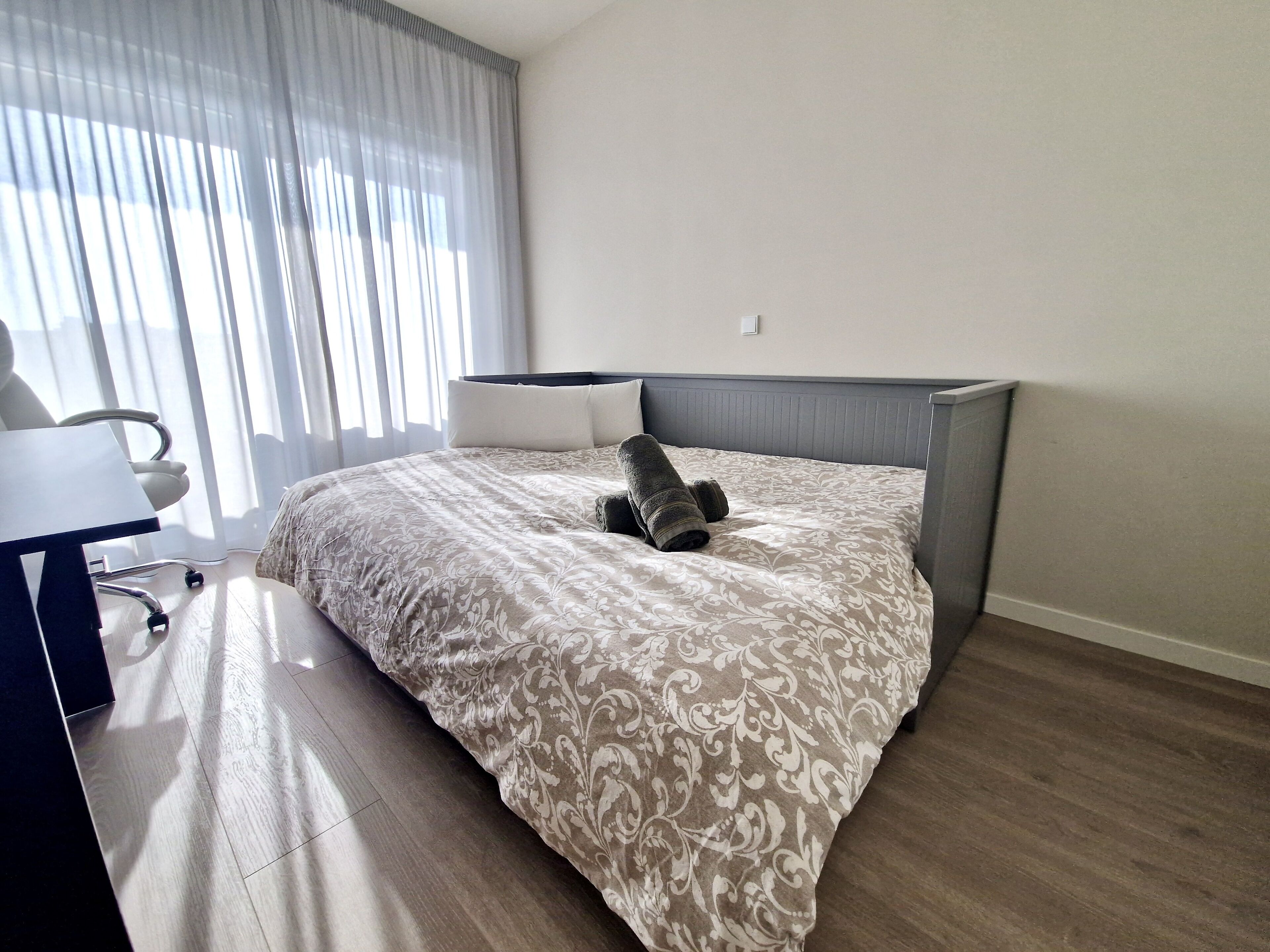 A hotel room with a bed, a desk, and a chair.