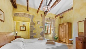 Un dormitorio con una cama grande, vigas de madera, pared de piedra y un armario de madera.