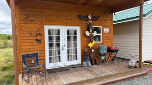 A wooden cabin with a porch, a bench, a grill, and a bear decoration. - Sockeye Chalet at Redbow (Sterling)