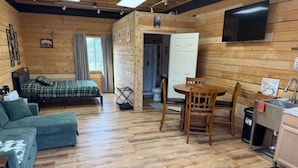 A cozy cabin with a bed, a sofa, a dining table, and a kitchen area. - Sockeye Chalet at Redbow (Sterling)
