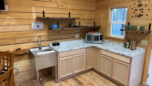 A compact kitchen with wooden walls, a granite countertop, and a small window. - Sockeye Chalet at Redbow (Sterling)