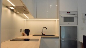 A modern kitchen with a built-in oven and microwave, a sink with a black faucet, and a light-colored countertop. - Luxury Studio in Gibraltar (Gibraltar)
