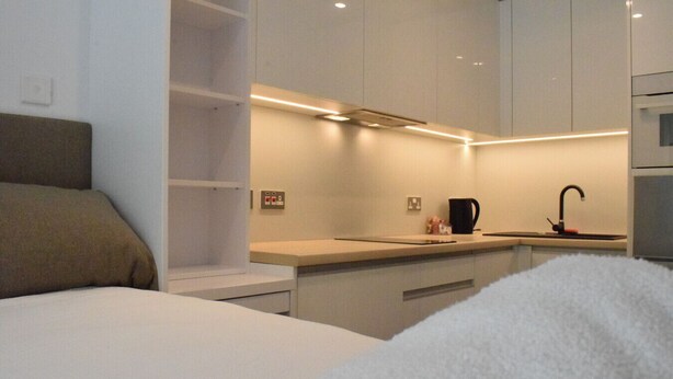 A modern, compact hotel room with a bed, a small kitchenette, and a bathroom. - Luxury Studio in Gibraltar (Gibraltar)