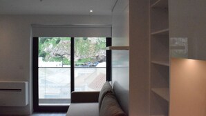 A modern room with a large sliding glass door leading to a balcony, a built-in bench, and a wall-mounted shelf. - Luxury Studio in Gibraltar (Gibraltar)
