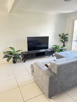 Relax in this stylish living room with a flat-screen TV, comfortable sofa, and potted plants.