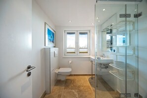 Ein kleines Badezimmer mit Toilette, Waschbecken und Duschkabine aus Glas.