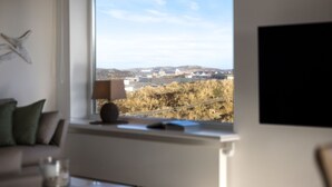 Una habitación con un ventanal amplio que ofrece vistas a un paisaje distante con edificios y colinas.