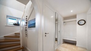 Una escalera conduce a un dormitorio con ventana, puerta y un espejo en la pared.