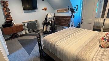 Une chambre à coucher comprenant un lit, un ventilateur de plafond, un fauteuil massant, une télévision et une décoration murale en bois.