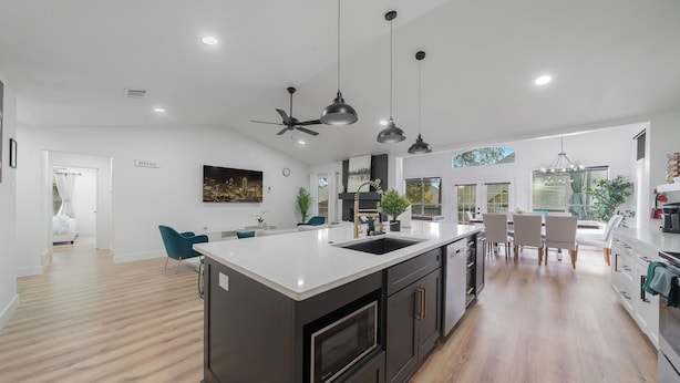 Una cocina moderna con una isla grande, muebles oscuros e iluminación colgante.