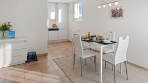 Une cuisine moderne avec des meubles blancs, une table à manger avec des chaises et un petit tabouret.