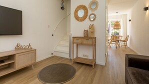 Una sala de estar moderna con piso de madera, una mesa redonda, un sofá y un televisor montado en la pared.
