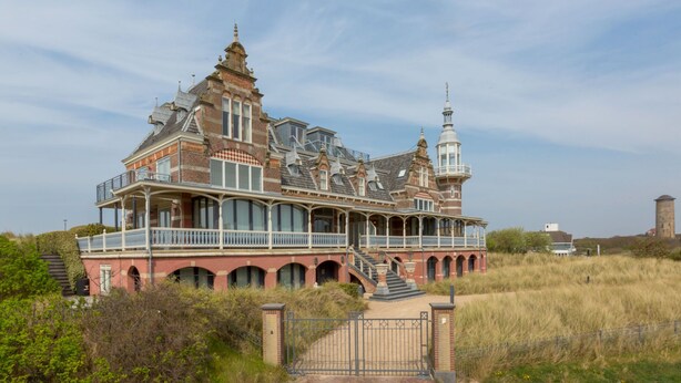 Una casa grande e histórica con varios niveles, una torre destacada y una entrada con portón.