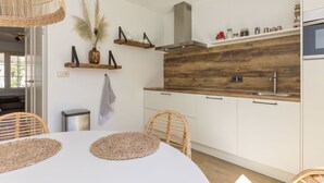 Una cocina moderna con gabinetes blancos, un protector contra salpicaduras de madera y un fregadero de acero inoxidable.