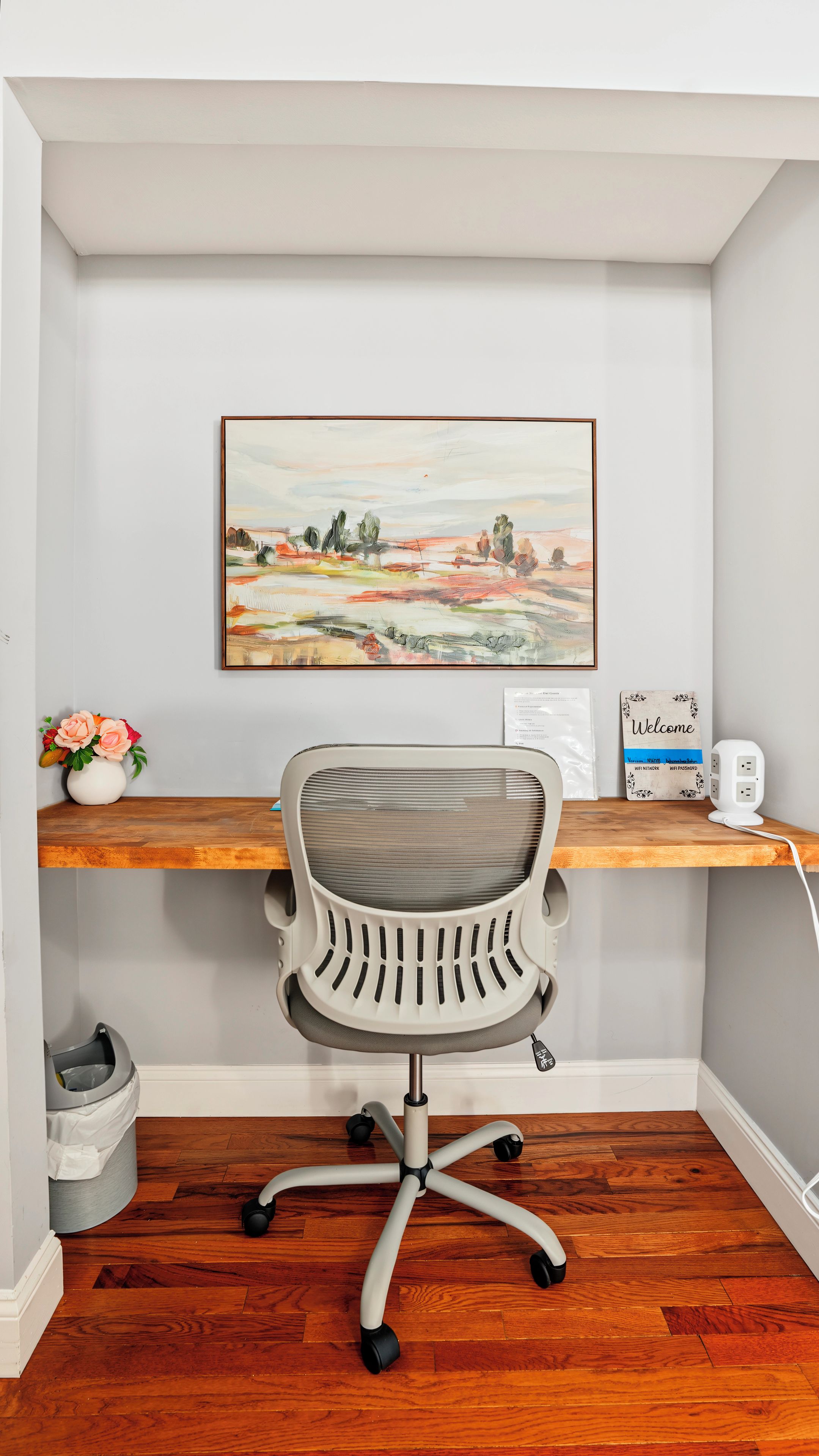 A home office with a desk, chair, and a painting on the wall.