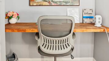 A home office with a desk, chair, and a painting on the wall.