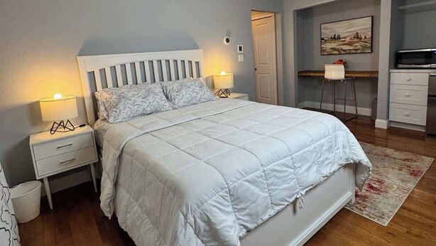 Une chambre à coucher comprenant un lit, des tables de chevet, une commode, un bureau et une chaise.