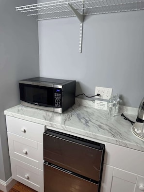 A kitchen with a microwave, a water dispenser, and a note about no smoking or vaping.