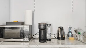 Un comptoir de cuisine équipé d’un four à micro-ondes, d’une machine à café Keurig, d’une bouilloire et de divers ustensiles de cuisine.