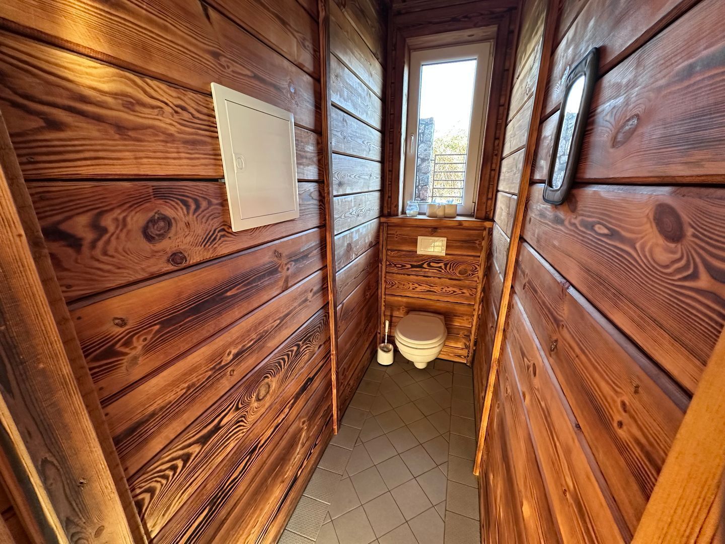 A wooden cabin with a small bathroom, a window, and a door.