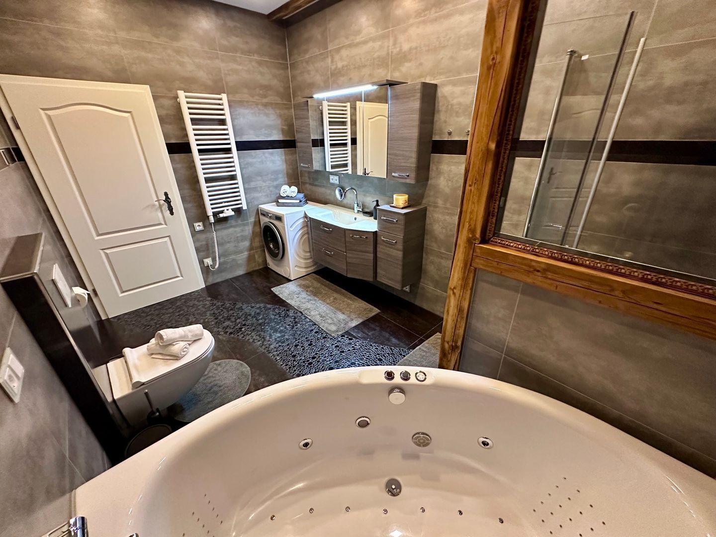 Un baño moderno con una bañera grande, una lavadora y un lavamanos.
