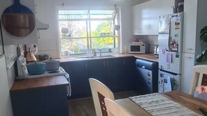 A modern kitchen with a dining area, wooden flooring, and a view of the outdoors.