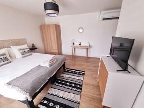 Ein modernes Schlafzimmer mit Bett, Nachttisch, Kleiderschrank, Schreibtisch und Fernseher.