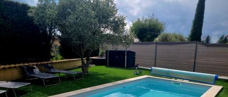 A rectangular swimming pool with a tiled edge, surrounded by artificial grass.
