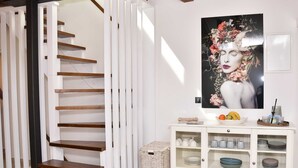 A staircase with wooden steps and white railings, a white cabinet with glass doors displaying dishes, and a framed floral artwork on the wall. - Old Town Rovinj Hidden Residence With Terrace (Rovinj)