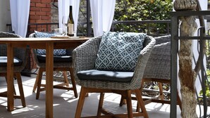 A patio area with wicker furniture, a table, and a bottle of wine. - Old Town Rovinj Hidden Residence With Terrace (Rovinj)