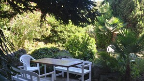 A patio with a table and two chairs, surrounded by lush greenery and a palm tree. - Charming Rovinj Haven (Rovinj)