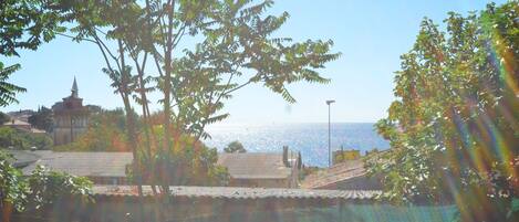 A coastal view with a building, trees, and a clear sky.