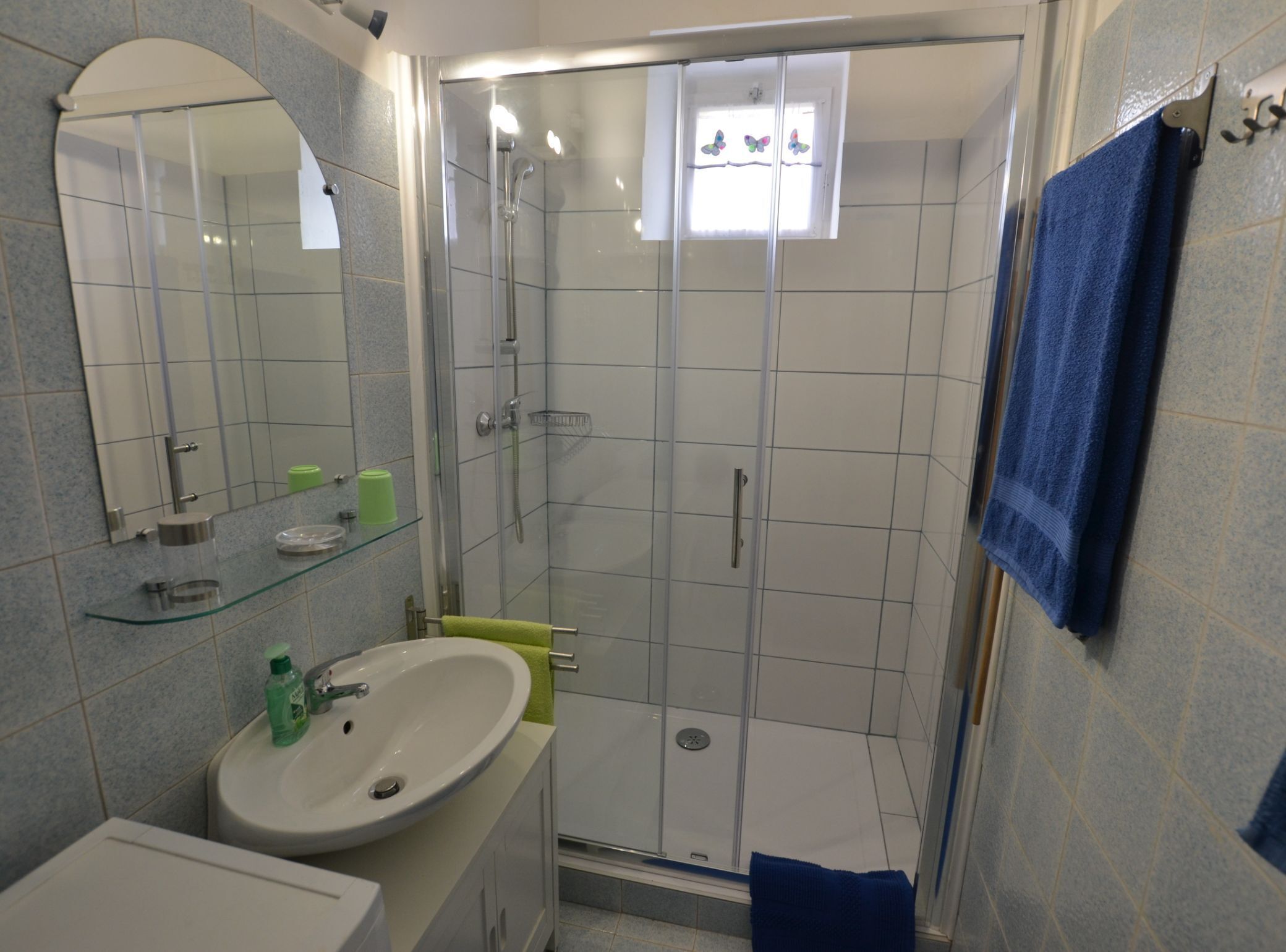 A bathroom with a glass-enclosed shower, a sink with a mirror, and a towel rack.