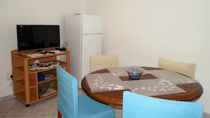 A small room with a television, a refrigerator, a wooden cabinet, and a round table with chairs. - Crikvenica Tranquil and Stylish Apartments With Sea View (Crikvenica)