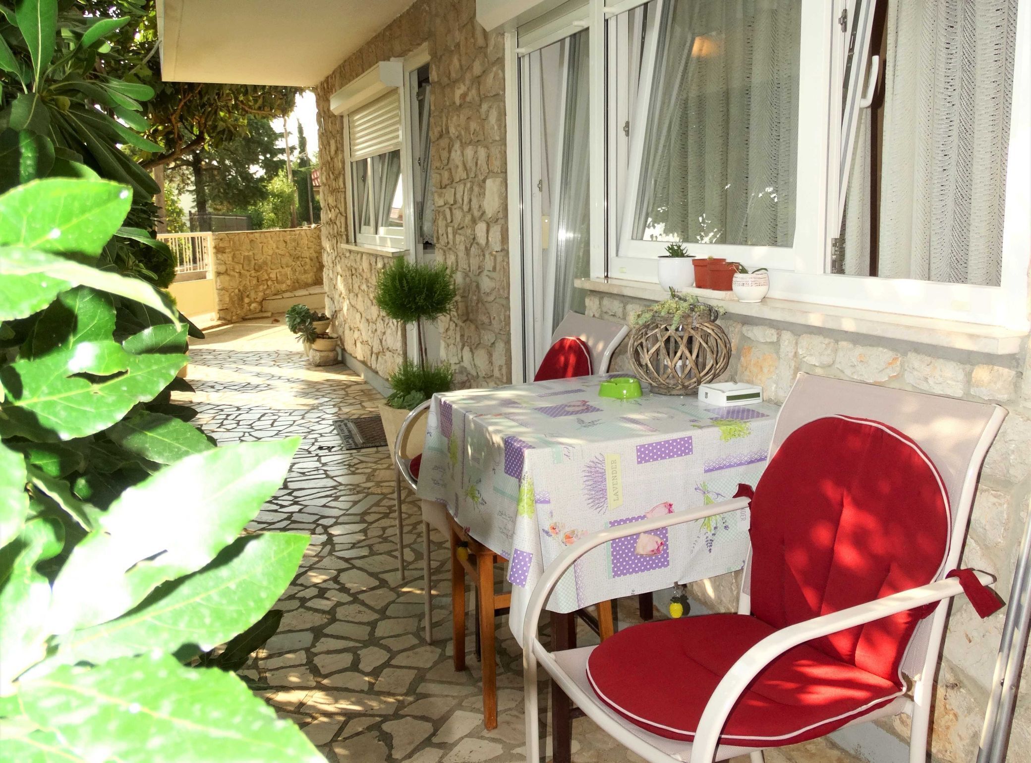 Une terrasse extérieure avec une table et une chaise, des murs en pierre et des plantes en pot.