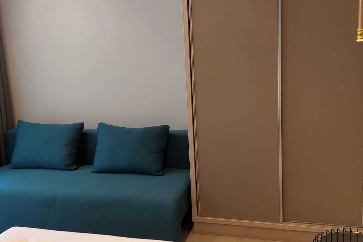 Ein Zimmer mit einem Bett, einer Schlafcouch mit zwei Kissen und einer Schiebetür.