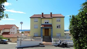 A two-story building with a tiled roof, a front entrance with steps, and a white fence. - Cozy Crikvenica Apartments With Sea View and Balcony (Crikvenica)