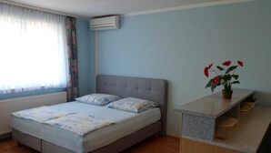 A bedroom with a bed, a nightstand, a potted plant, and a window with curtains. - Cozy Crikvenica Apartments With Sea View and Balcony (Crikvenica)